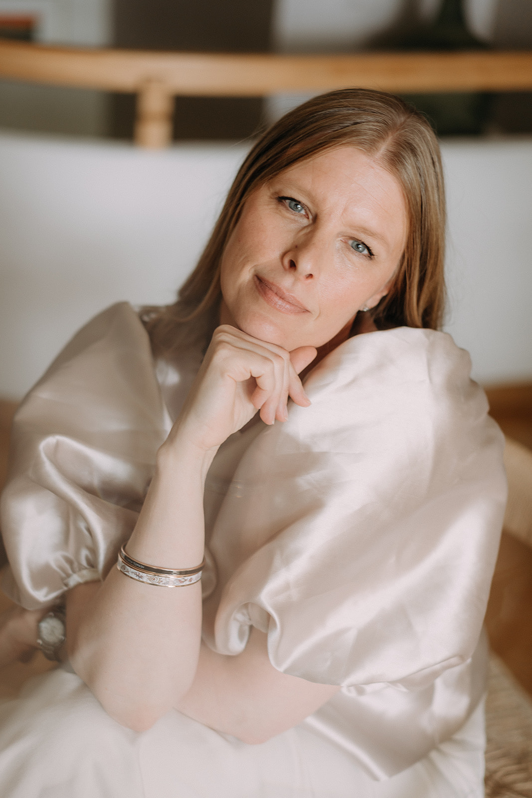 Päivi Halt seated with her hand gently beneath her chin, looking calmly at the camera